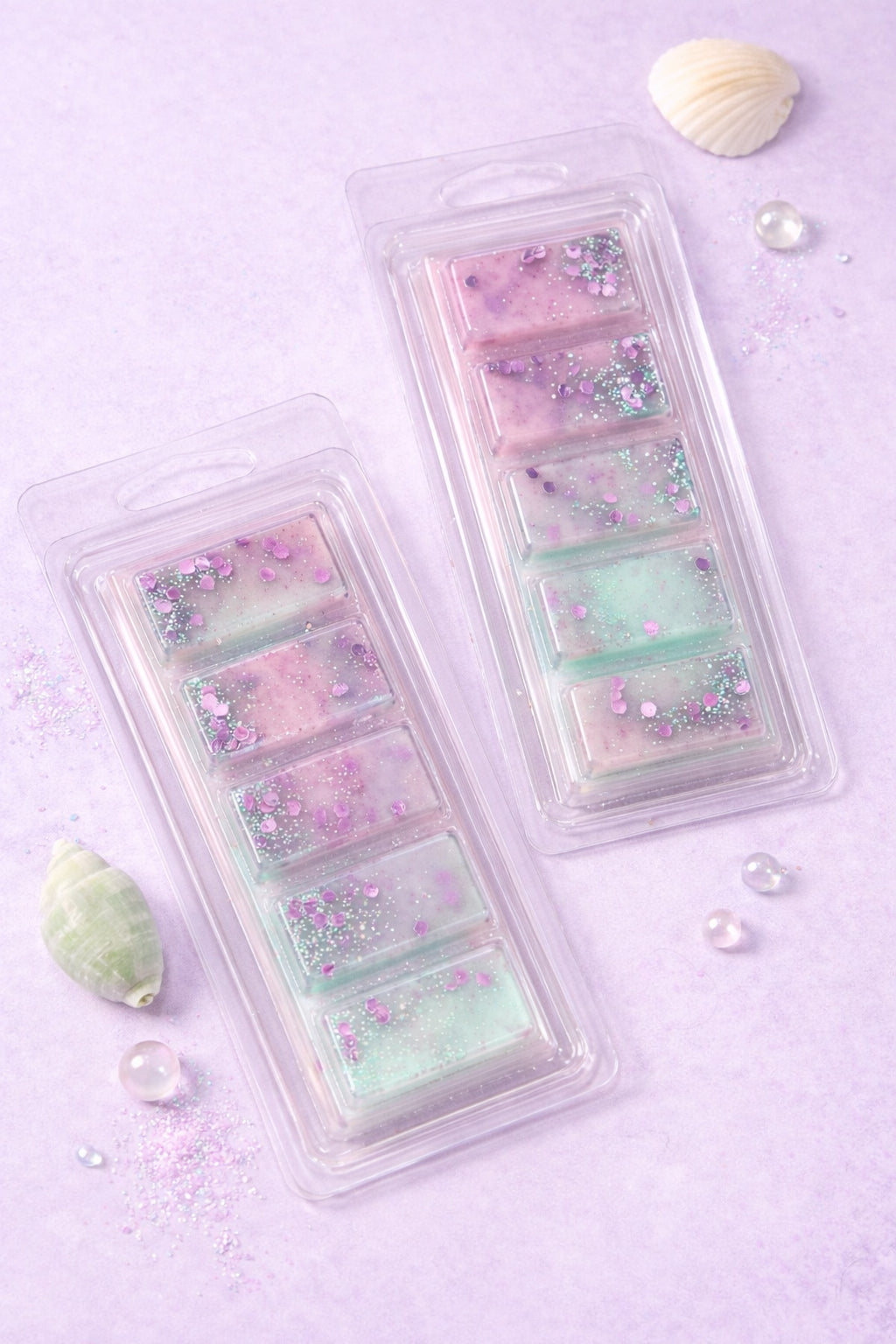 Two plastic containers filled with pastel-colored wax melts on a light purple background.