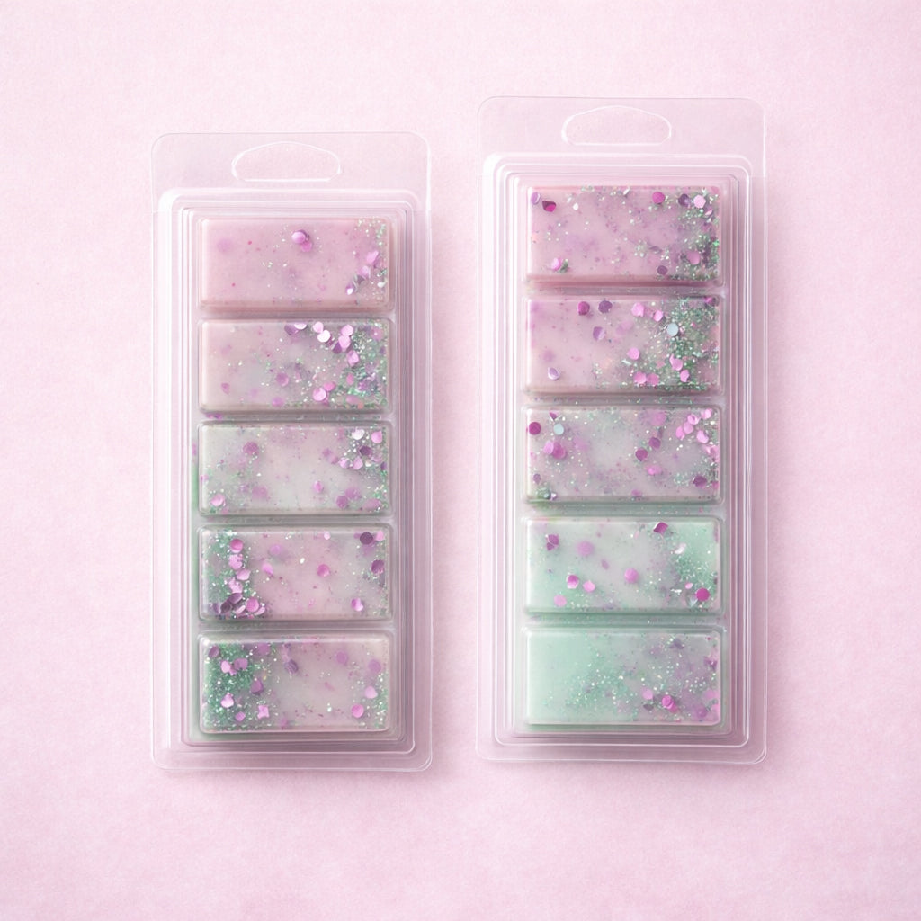 Two plastic molds with pastel-colored wax melts on a pink background