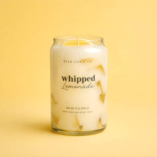 Glass candle labeled 'Whipped Lemonade' by Elle Lux & Co on a yellow background